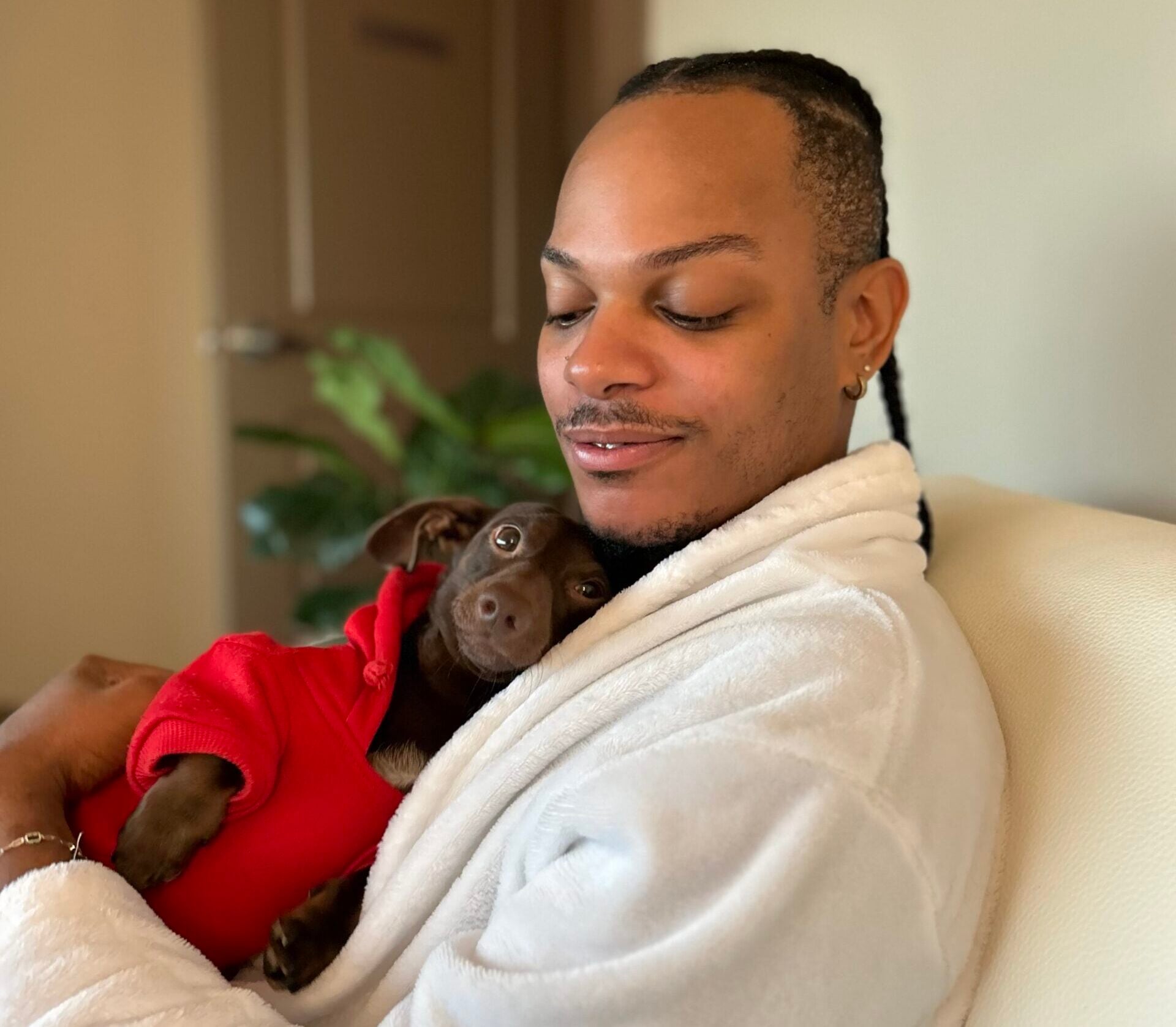 Man in robe holding a dog in a sweater both looking happy and relaxed