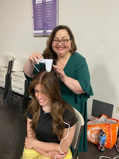 Woman smiles as she's scanning another woman's head. Both seem to be enjoying the process